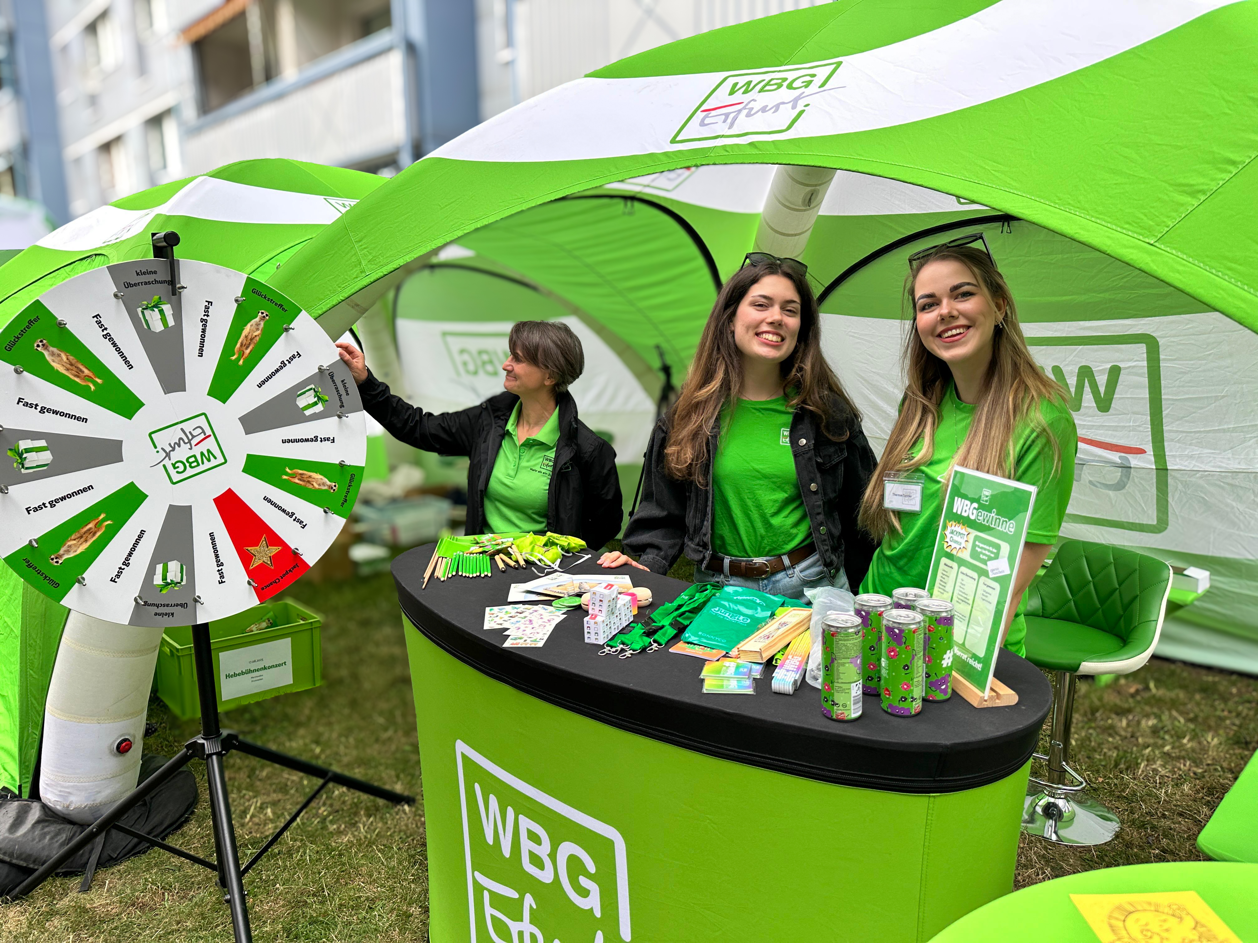 WBG-Erfurt-Infostand mit Glücksrad Drei Frauen an einem grünen Infostand mit Glücksrad