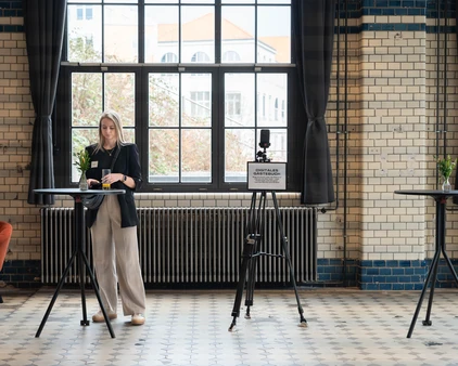 Besucherin mit Glas in der Hand steht an einem Stehtisch
