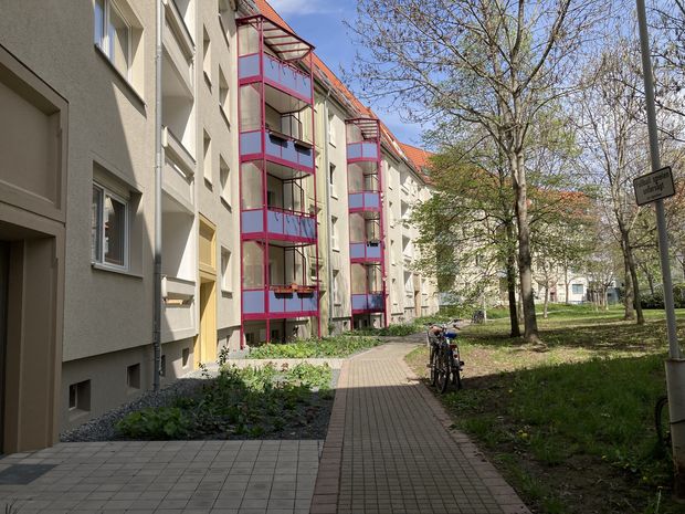 Wohnblock mit heller Fassade und rot-blauen Balkonen an der Außenwand