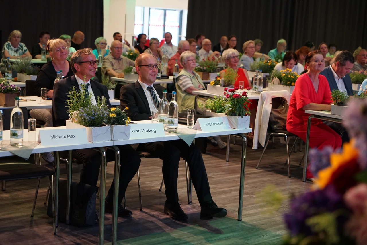 Vertreterversammlung der WBG Erfurt Publikum an Tischen sitzend mit Tischpflanzen und Namensschildern