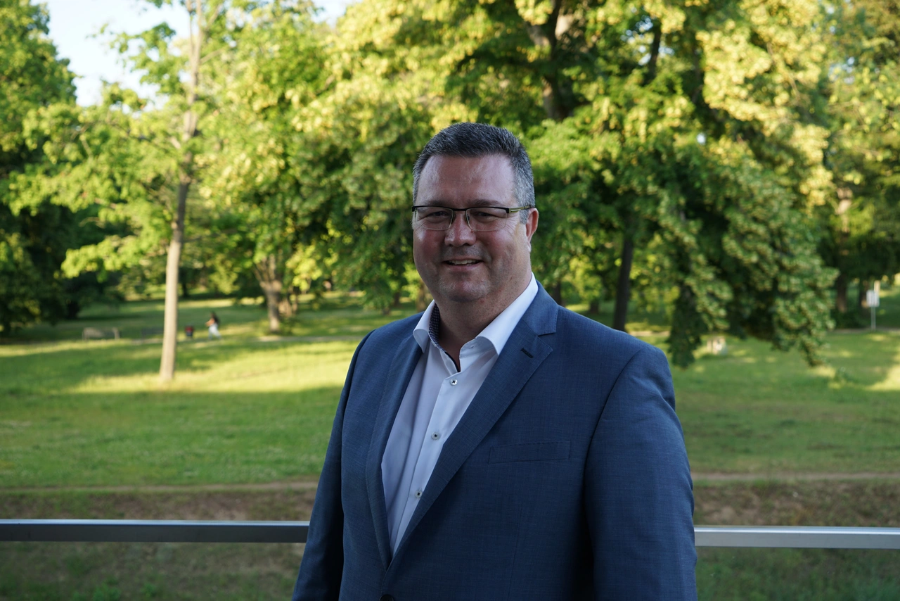 Herr Dr. Reik Kalnbach bei der Vertreterversammlung Porträt von Herrn Dr. Reik Kalnbach vor einer Grünanlage