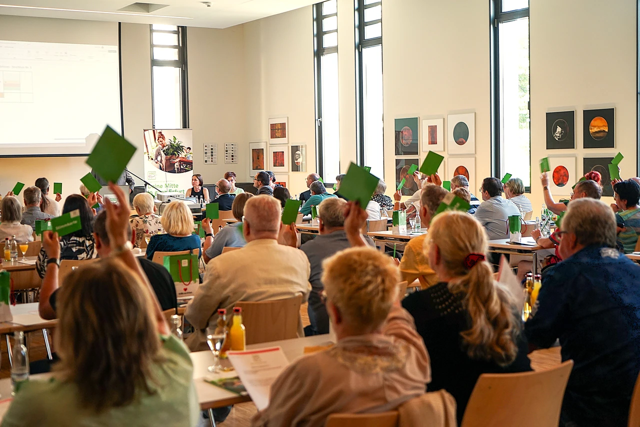 Veranstaltung der WBG Erfurt mit Menschen, die Abstimmkarten heben