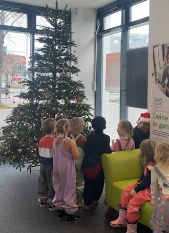 Kita Weihnachtsbaumschmücken Kinder stehen vor einem geschmückten Weihnachtsbaum