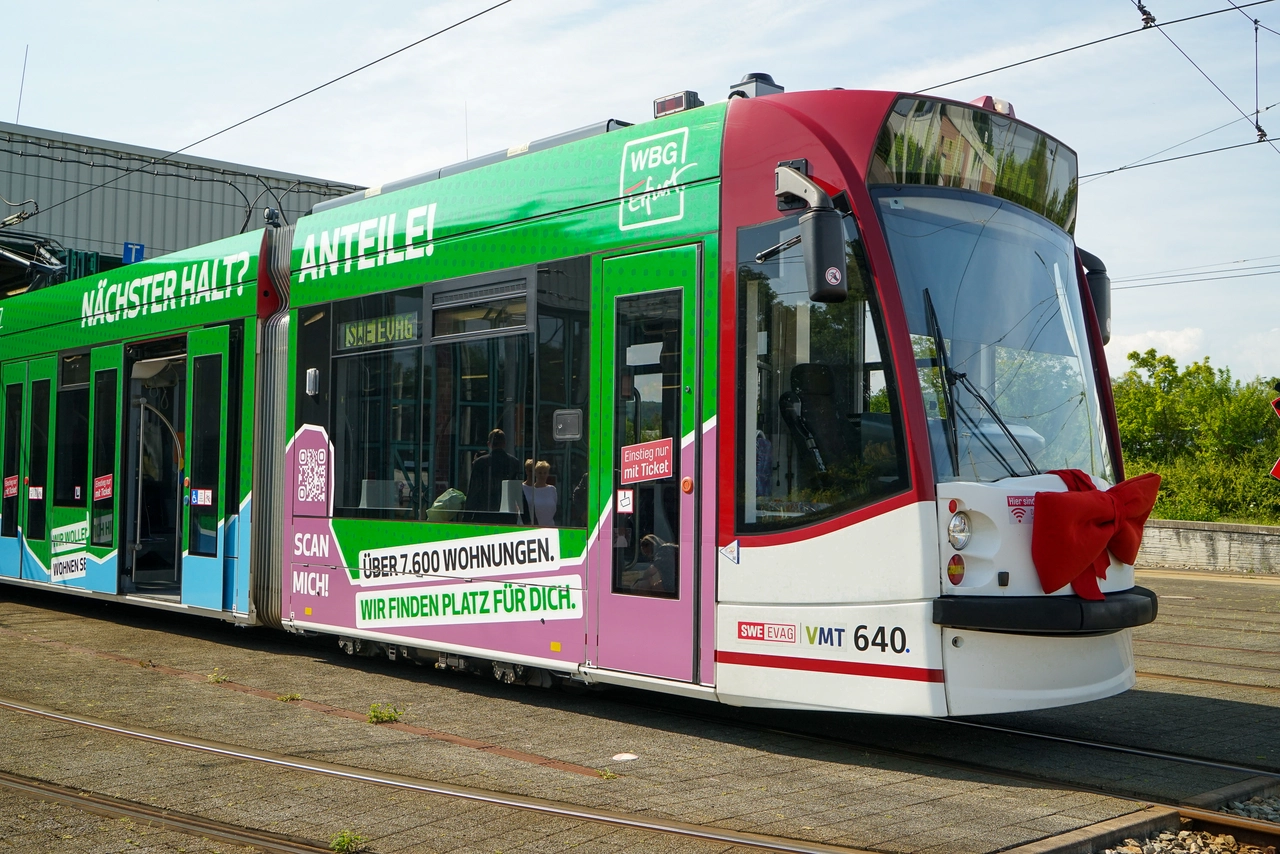 Straßenbahn Außenwerbung Grün-rote Straßenbahn mit Werbebotschaften und roter Schleife