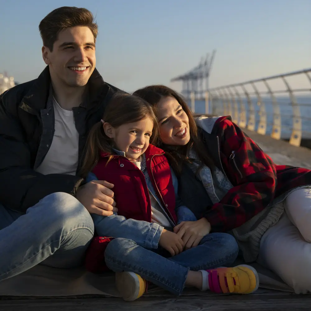 Familie auf einem Steg mit Blick auf das Meer, lächelnd