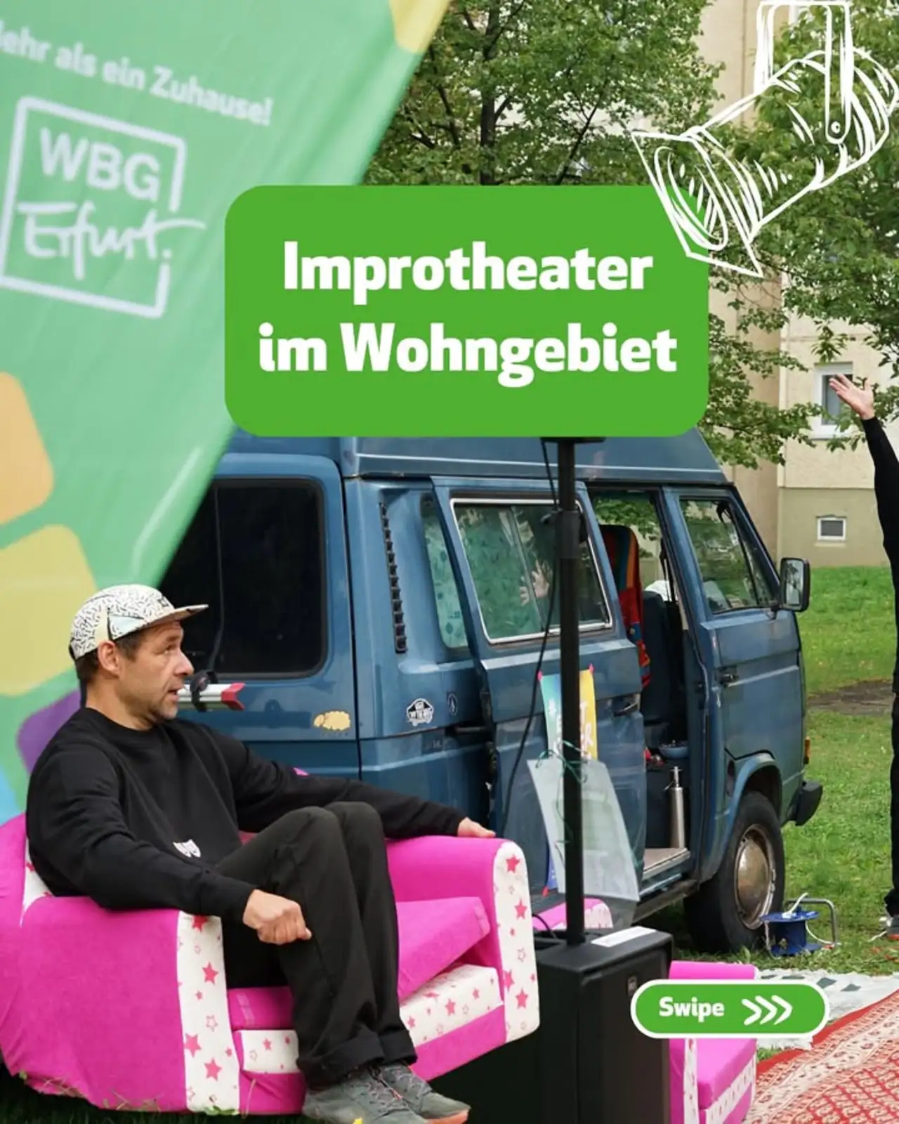 Improtheater im Wohngebiet Ein Mann mit Kappe und schwarzem Pullover sitzt draußen in einem pinkfarbenen Sessel neben einem blauen Oldtimer-Van vor einem Wohngebäude